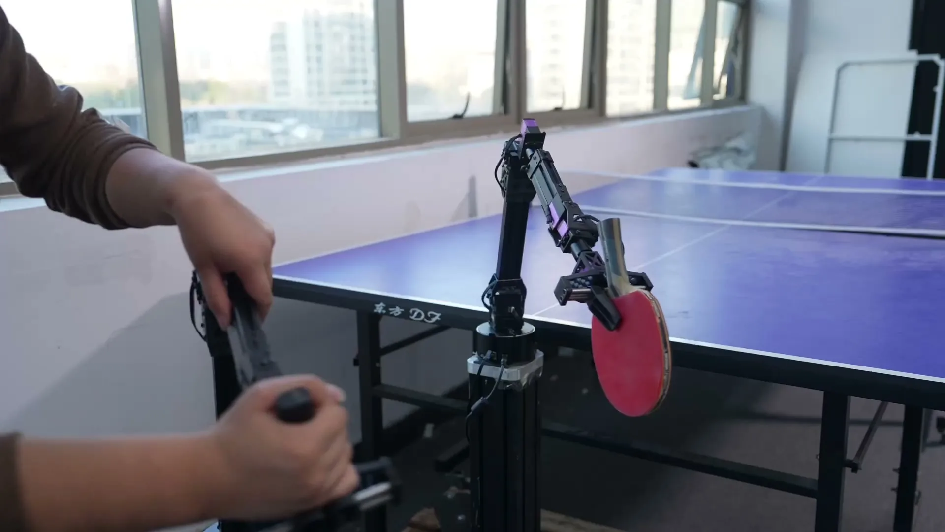 Un D1-T teleoperado sostiene una raqueta junto a una mesa de ping-pong